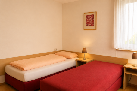 Zimmer 8 Zwei Betten in einem hellen Zimmer, neben Nachttischen mit Lampen. Minimalistische Einrichtung.