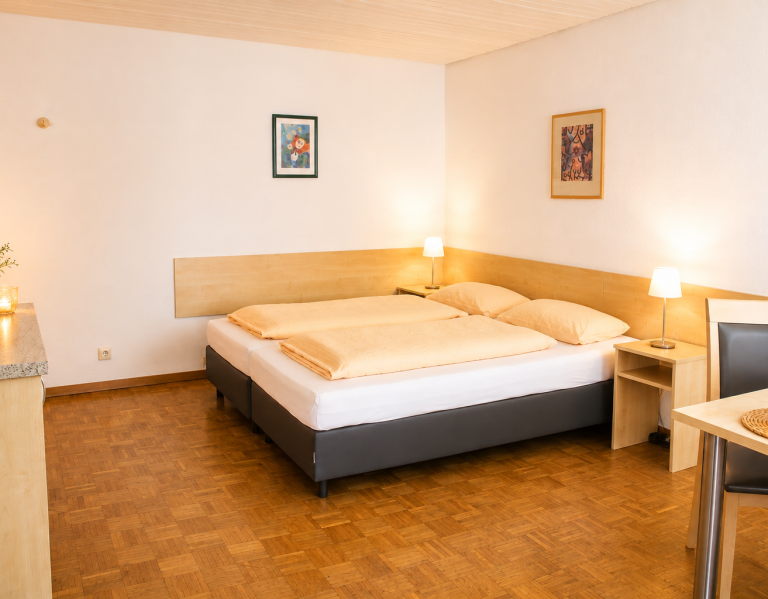 Betten Gästezimmer Helles Hotelzimmer mit zwei Betten, Nachttisch und einempflanzen.