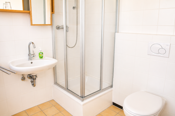 Badezimmer Kleinbad mit Dusche, Waschbecken und Toilette in heller Farbgebung.