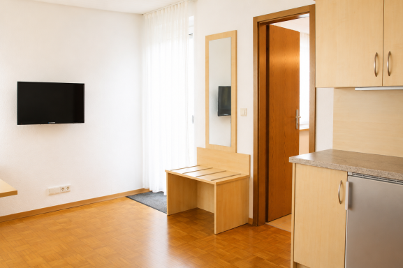 Zimmereinrichtung Helle, moderne Wohnung mit Fernseher, Tisch und Stuhl sowie Küchenbereich.