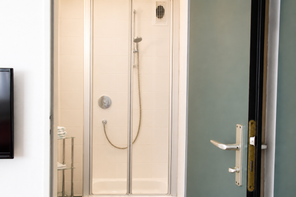 Badezimmer Duschkabine mit Glastür, Wandhahn und Handbrause in einem modernen Badezimmer.